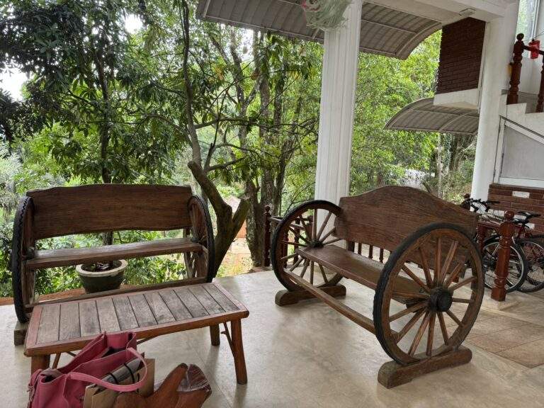Kaffeeplantage in Kandy: Zwei Holzbänke und ein Tisch mit Wagenrädern in einem Außenbereich. - buchbar im Reisebüro Budde Urlaubseisen