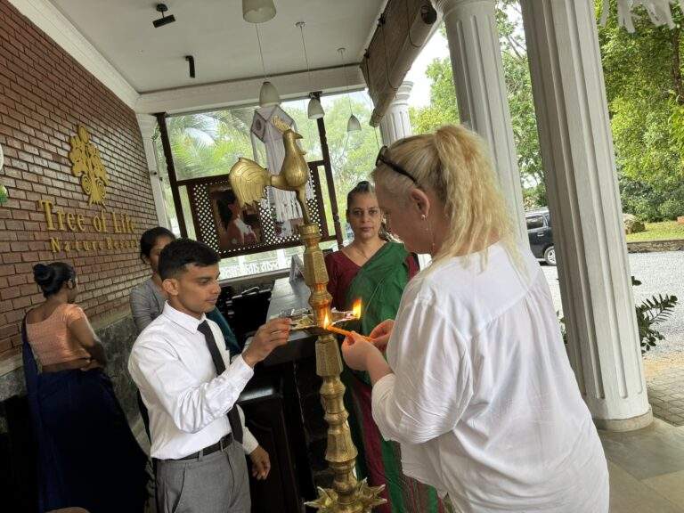 Kaffeeplantage in Kandy: Eine Person zündet eine Lampe an, während eine andere Person in traditioneller Kleidung zusieht. - buchbar im Reisebüro Budde Urlaubseisen