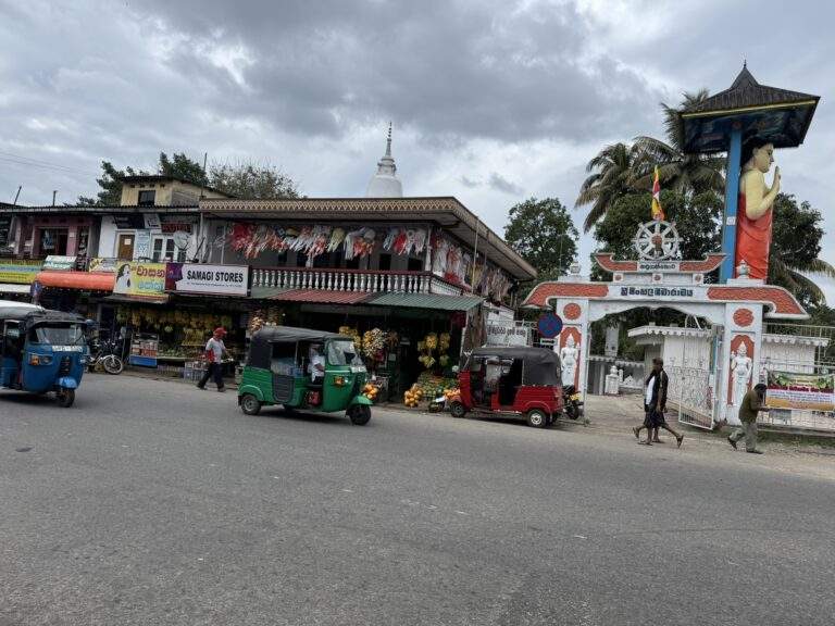 Sri Lanka Urlaub buchen: Straßenszene mit mehreren Tuk-Tuks und Geschäften in Sri Lanka unter bewölktem Himmel. - buchbar im Reisebüro Budde Urlaubseisen