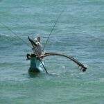 Ein Fischerboot mit Angeln, das auf dem Wasser schwimmt, umgeben von Wellen. - Sri Lanka Urlaub buchen