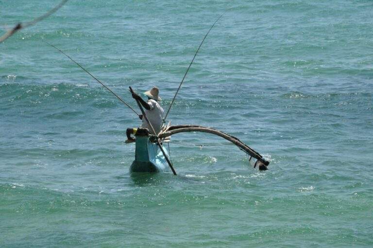 Ein Fischerboot mit Angeln, das auf dem Wasser schwimmt, umgeben von Wellen. - Sri Lanka Urlaub buchen