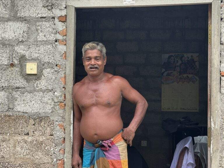 Sri Lanka Urlaub buchen: Ein Mann steht im Eingangsbereich eines Hauses und trägt einen bunten Sarong. - buchbar im Reisebüro Budde Urlaubseisen