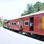 Ein roter Zug mit offenen Fenstern, der an einem Bahngleis in Sri Lanka hält. - Sri Lanka Urlaub buchen