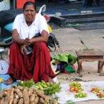 Frau sitzt auf dem Boden und verkauft frisches Obst und Gemüse, darunter Bananen und Süßkartoffeln. - Sri Lanka Urlaub buchen