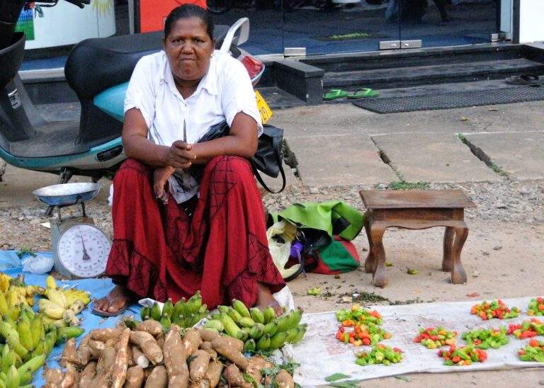 Frau sitzt auf dem Boden und verkauft frisches Obst und Gemüse, darunter Bananen und Süßkartoffeln. - Sri Lanka Urlaub buchen