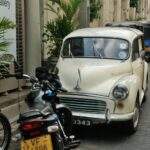 Ein weißes Auto parkt an einer Straße in Sri Lanka, umgeben von anderen Fahrzeugen und Pflanzen. - Sri Lanka Urlaub buchen