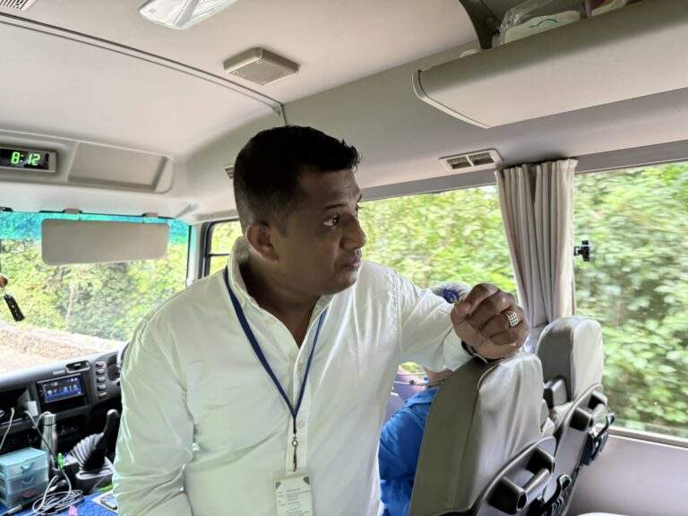Sri Lanka Urlaub buchen: Mann in weißem Hemd steht im Bus und spricht mit Passagieren während einer Reise. - buchbar im Reisebüro Budde Urlaubseisen