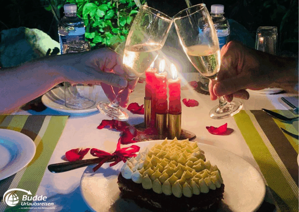 Praana Ayurvedic Boutique Hotel: Zwei Gläser Sekt stoßen an, während ein Kuchen mit Sahne auf dem Tisch steht. - buchbar im Reisebüro Budde Urlaubseisen