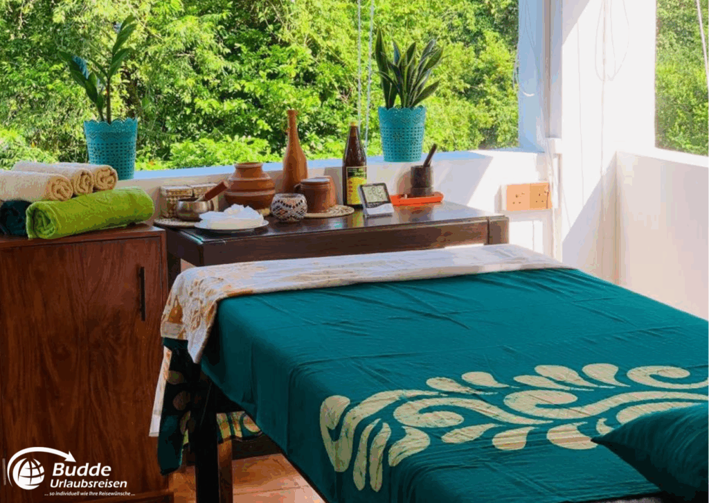 Ein Massagetisch in einem Ayurveda Behandlungsraum mit grüner Tischdecke und verschiedenen Utensilien. - buchbar im Reisebüro Budde Urlaubseisen