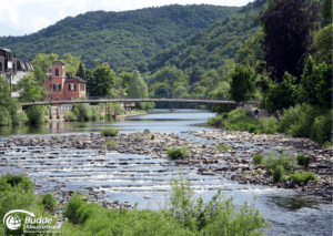 Urlaub an der Nahe: Fluss mit fließendem Wasser, einer Brücke und grüner Ufervegetation in Bad Kreuznach. - buchbar im Reisebüro Budde Urlaubseisen