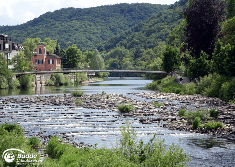 Urlaub an der Nahe: Fluss mit fließendem Wasser, einer Brücke und grüner Ufervegetation in Bad Kreuznach. - buchbar im Reisebüro Budde Urlaubseisen