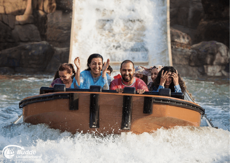 Disneyland Paris: Sechs Personen in einem Boot auf einer Wasserbahn, die durch Wasserfälle fahren und lachen.