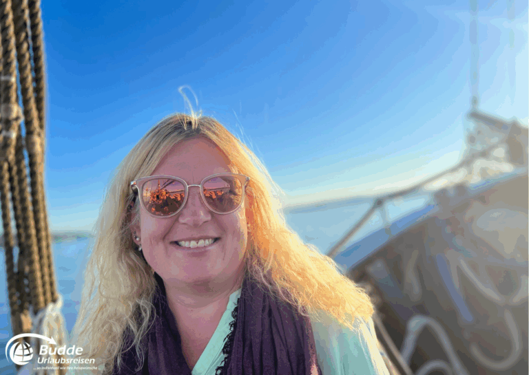 Norwegen Urlaub: Frau mit blonden Haaren und Sonnenbrille lächelt auf einem Boot bei Sonnenuntergang. Norwegen Urlaub: Frau mit blonden Haaren und Sonnenbrille lächelt auf einem Boot bei Sonnenuntergang.