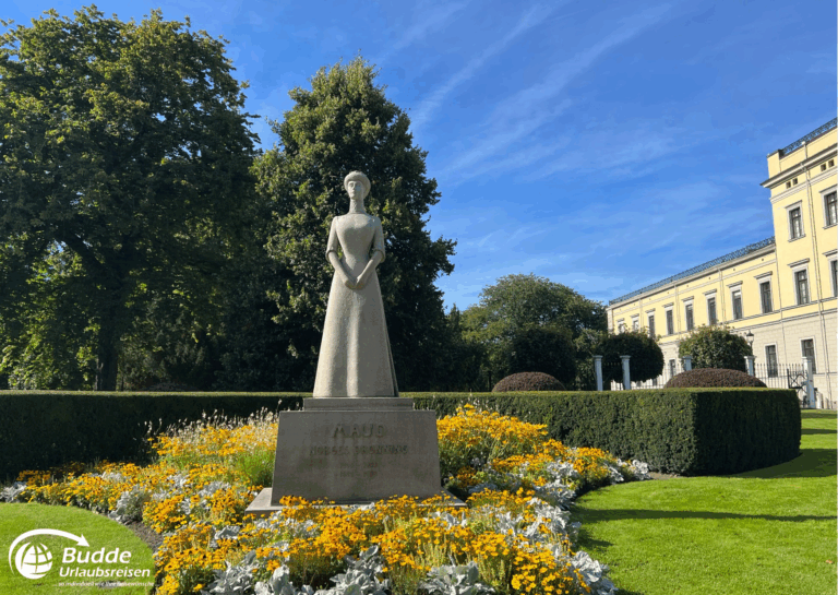 Norwegen Urlaub: Steinskulptur einer Frau in einem Park mit bunten Blumen und Bäumen im Hintergrund. Norwegen Urlaub: Steinskulptur einer Frau in einem Park mit bunten Blumen und Bäumen im Hintergrund.