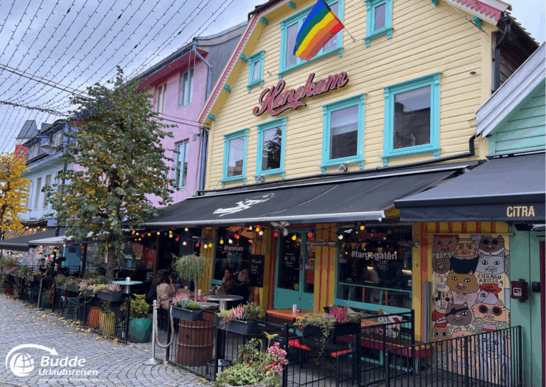 Norwegen Urlaub: Buntes Restaurant mit Tischen im Außenbereich und einer Regenbogenflagge in Oslo. Norwegen Urlaub: Buntes Restaurant mit Tischen im Außenbereich und einer Regenbogenflagge in Oslo.