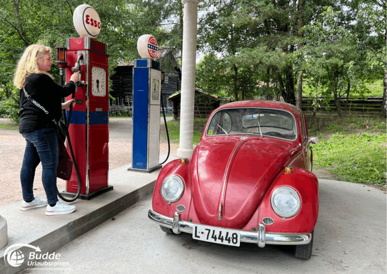 Norwegen Urlaub: Roter Volkswagen Käfer parkt an einer vintage Tankstelle mit zwei Zapfsäulen. Norwegen Urlaub: Roter Volkswagen Käfer parkt an einer vintage Tankstelle mit zwei Zapfsäulen.