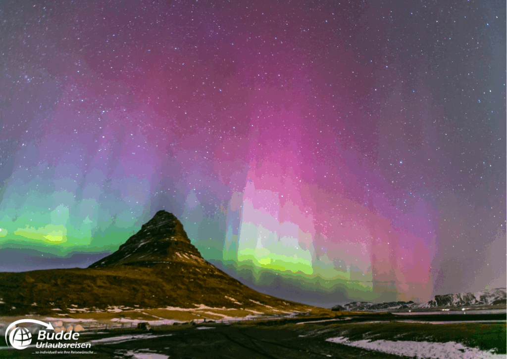 Reisetrends 2026: Nordlichter über dem Kirkjufell-Berg in Island mit bunten Lichtern am Nachthimmel.