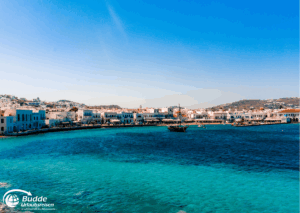 Strandurlaub Griechenland Insel Mykonos Küstenansicht von Mykonos mit klarem Wasser und Gebäuden im Hintergrund.