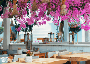 Strandurlaub Griechenland Insel Mykonos Ein Restaurant mit Holzstühlen und Tischen, dekoriert mit Bougainvillea und Laternen in Mykonos.