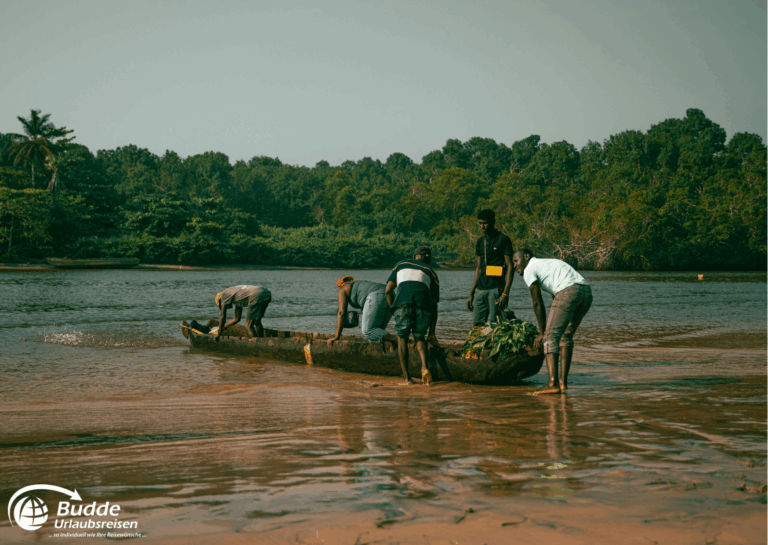 Gruppe von Männern, die an einem traditionellen Boot in Angola arbeiten, während sie im Wasser stehen. - Urlaub in Angola buchen