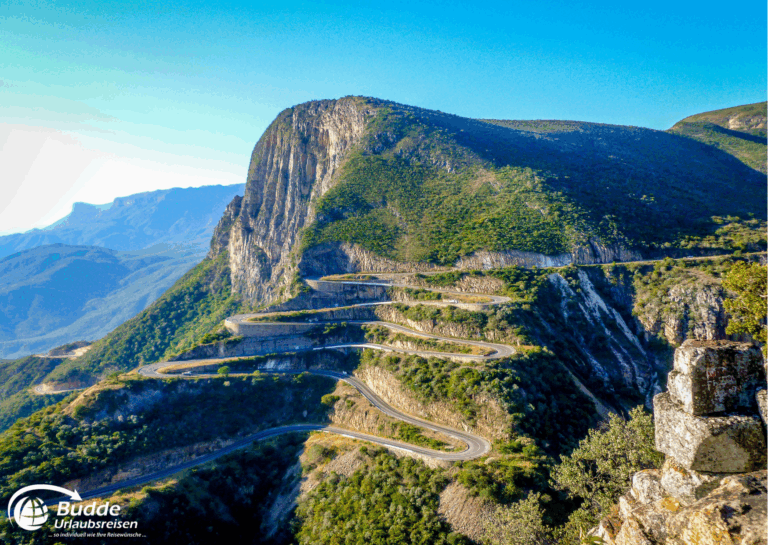 Kurvenreiche Straße, die sich um einen Berg in Angola schlängelt, mit grüner Vegetation im Hintergrund. - Urlaub in Angola buchen
