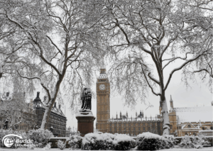 Weihnachtsshopping nach London: Schneebedeckte Bäume und der Big Ben im Hintergrund in einer winterlichen Szene.