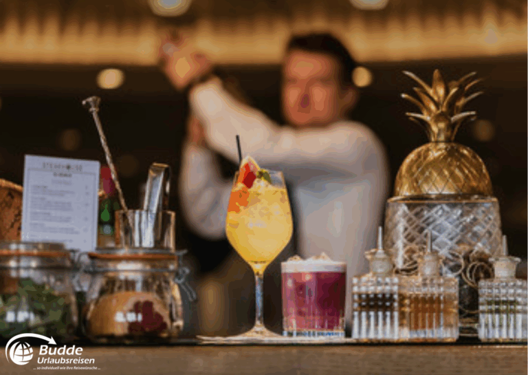 Weltreise Queen Mary 2: Ein Cocktail mit bunten Früchten und einer dekorativen Ananas im Hintergrund auf einer Bar.