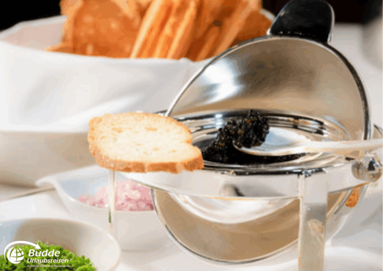 Weltreise Queen Mary 2: Silberne Caviar-Servierplatte mit einem Stück Brot und Beilagen wie Zwiebeln und Kräutern.