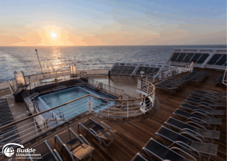 Weltreise Queen Mary 2: Schwimmbadbereich auf einem Kreuzfahrtschiff mit Liegen und Blick auf das Meer bei Sonnenuntergang.