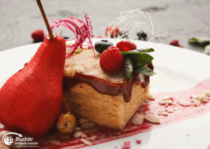 exquisitesten Restaurants: Ein Stück Dessert mit einer Birne, Beeren und einer Schicht Karamell auf einem Teller.