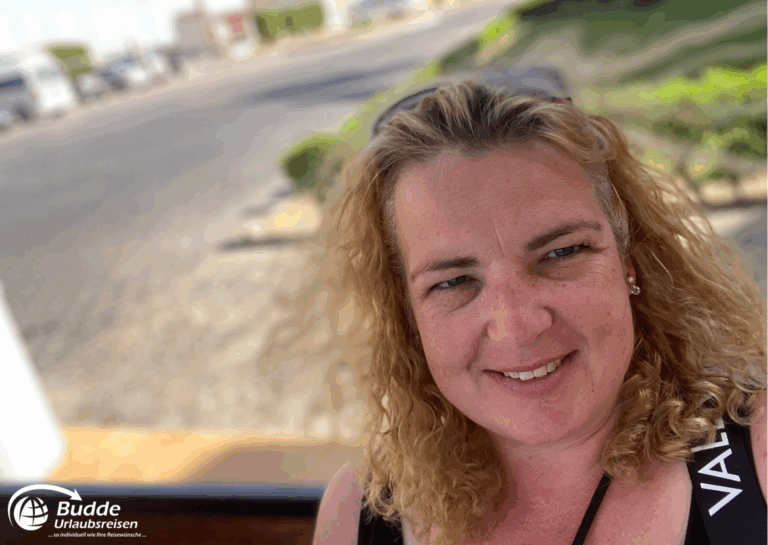 unvergessliche Urlaubsreise: Frau mit lockigem Haar und lächelndem Gesicht, aufgenommen an einer Haltestelle.