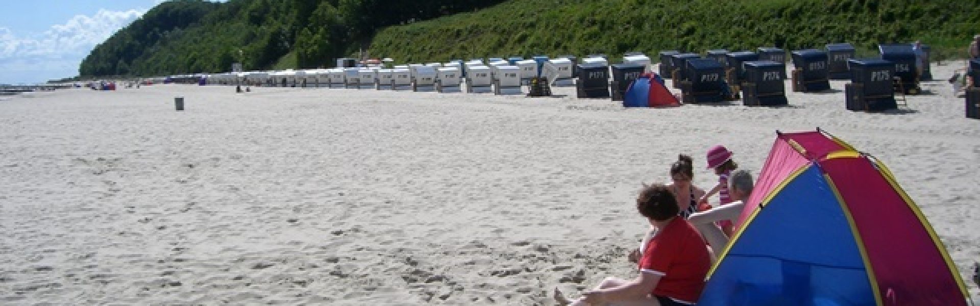 Familienurlaub-Ostsee-Babyreise-Usedom-Sandstrand Das entzückende Bild zeigt eine fröhliche Familie, die einen unvergesslichen Familienurlaub an der Ostsee auf der Insel Usedom verbringt. Sie haben sich einen wunderschönen Platz am endlosen Sandstrand gesichert. Das Baby spielt vergnügt im weichen Sand und die Eltern beobachten liebevoll, wie es die ersten Schritte im flachen Wasser unternimmt. Ein Familienurlaub auf Usedom bietet die perfekte Kulisse für erholsame Tage am Strand, gemeinsame Spaziergänge entlang der Küste und wertvolle Zeit miteinander. Buchen Sie jetzt Ihren Familienurlaub auf Usedom und genießen Sie unbeschwerte Tage am Ostseestrand.
