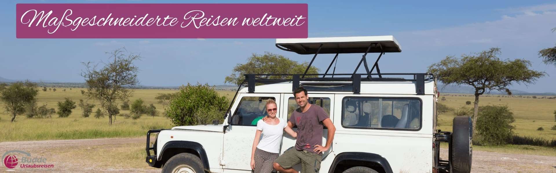 Urlaubsreisen Ein Geländewagen steht auf einer offenen Fläche mit zwei Personen, die daneben posieren.
